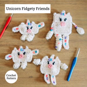 Puede incluir: Cuatro juguetes fidget de unicornio de ganchillo blanco con narices rosas, detalles azules y rosas y ojos negros se muestran sobre una superficie de madera. Los juguetes tienen forma cuadrada o redondeada. El texto "Unicorn Fidgety Friends" y "Crochet Pattern" son visibles.