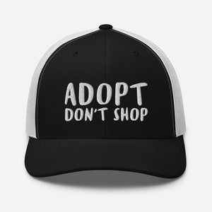 May include: Black and white trucker hat with the text "ADOPT DON'T SHOP" in white embroidery.