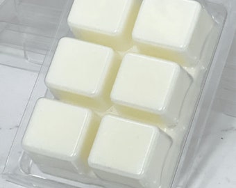 Op de afbeelding: Een transparante plastic bak met zes witte wasblokjes. De wasblokjes zijn vierkant en zijn gerangschikt in twee rijen van drie.