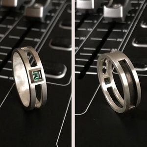 Könnte beinhalten: Zwei silberne Ringe mit einem grünen Edelstein. Ein Ring hat einen quadratischen Edelstein und der andere einen runden Edelstein.