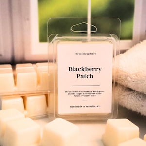 May include: A white wax melt with the text "Royal Daughters Blackberry Patch" and a quote from Proverbs 31:25. The wax melt is packaged in a clear plastic container with a hanging loop.