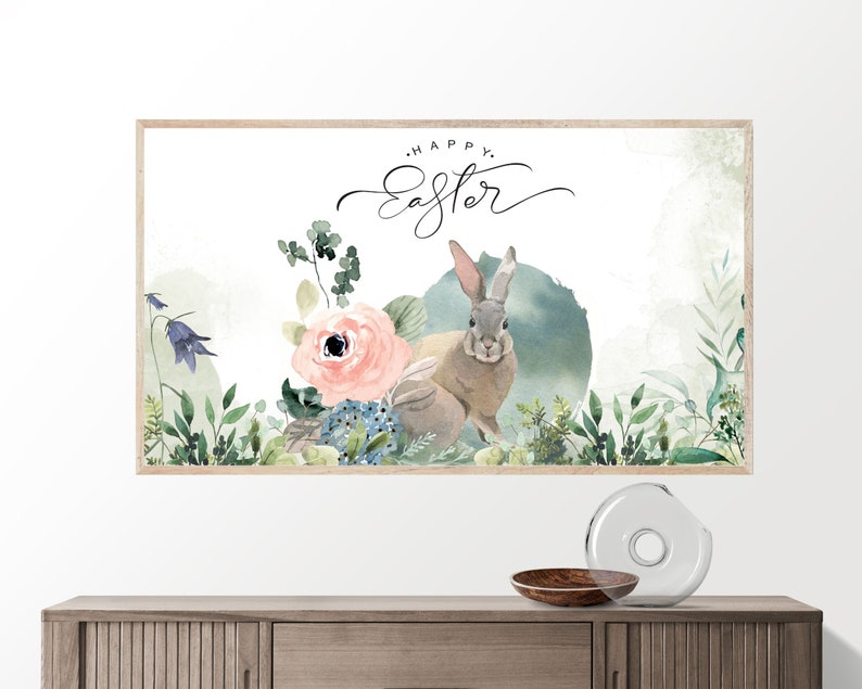May include: A watercolor painting of a bunny rabbit with a floral arrangement. The bunny is brown and gray with long ears. The flowers are pink, blue, and green. The text "Happy Easter" is written in black cursive above the bunny.