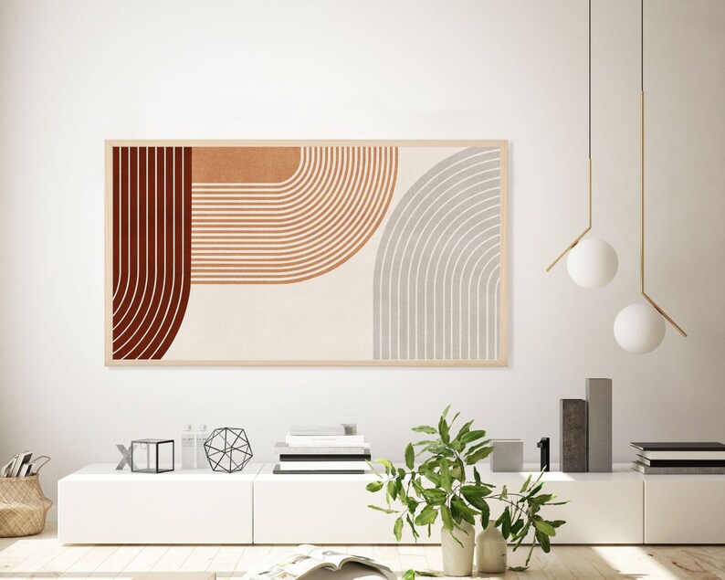 May include: A framed abstract art print with geometric shapes in shades of red, orange, and gray. The print is hanging on a white wall above a white shelf with decorative objects.