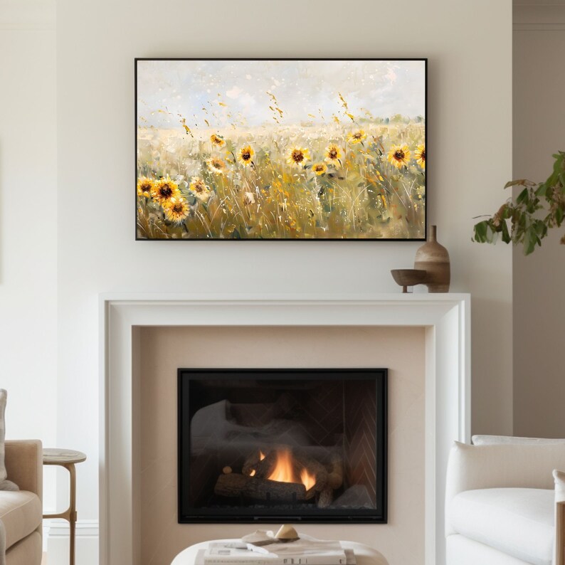 May include: A painting of a field of sunflowers in a rustic setting. The sunflowers are yellow with brown centers and are set against a background of green grass and a blue sky. The painting is framed in black and is hanging above a fireplace.