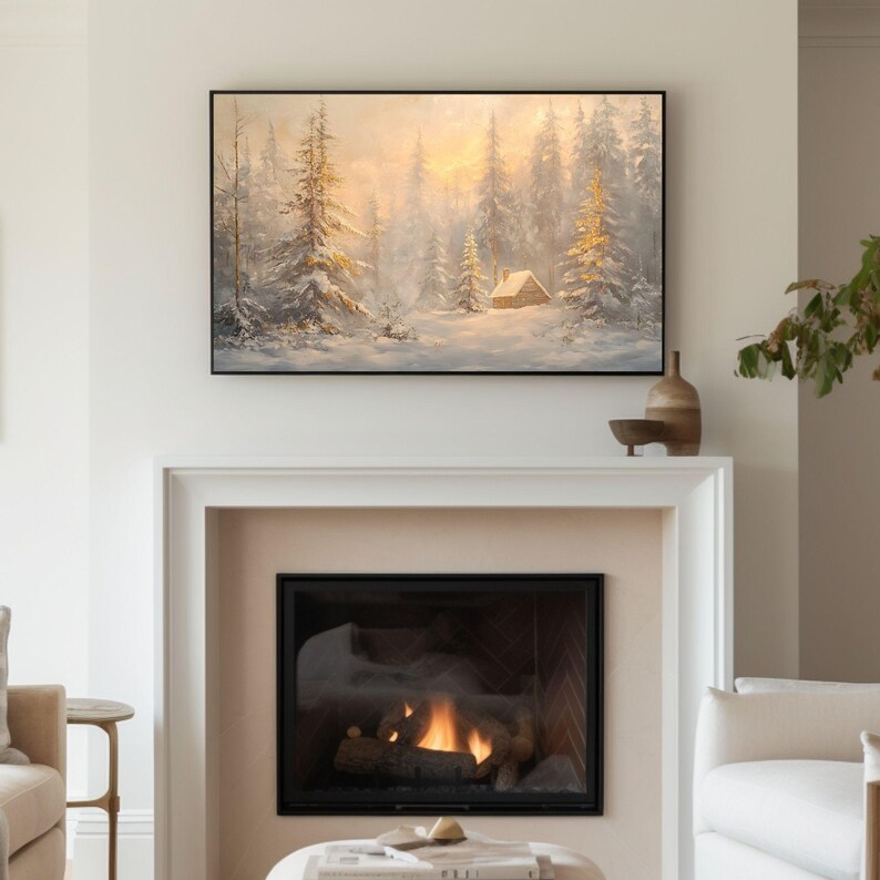 May include: A painting of a snowy forest scene with a small cabin in the distance. The sun is shining through the trees, creating a warm glow. The painting is framed in black and hanging above a fireplace.