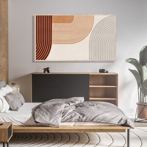 May include: A bedroom interior with a modern bed, a wooden nightstand, and a black and wood cabinet with shelves. A large abstract print with red, orange, and gray geometric shapes hangs on the wall above the cabinet. A potted plant with green leaves sits on the floor next to the cabinet.