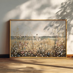 Op de afbeelding: Een ingelijst schilderij toont een figuur in een wit gewaad die met een kind door een veld met wilde bloemen loopt. Het kunstwerk heeft een warm kleurenpalet met een gouden lijst en is geplaatst tegen een bewolkte lucht.
