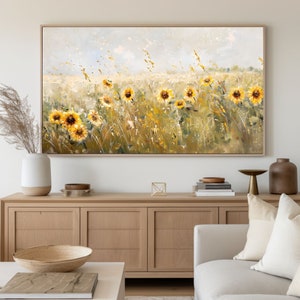 May include: A painting of a field of sunflowers in a light blue sky with white clouds. The sunflowers are yellow with brown centers and are in various stages of bloom. The field is green with tall grass and some brown stalks. The painting is framed in a light wood frame.