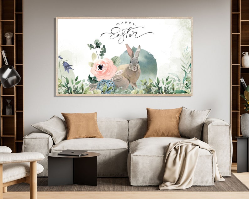 May include: A watercolor painting of a bunny rabbit in a field of flowers. The text "Happy Easter" is written in cursive above the bunny. The painting is framed in a light wood frame.