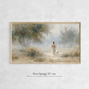 May include: A framed landscape print depicts a figure in a white robe with a staff, walking with a sheep on a path. The artwork has a soft, muted color palette with a serene, pastoral scene. Text at the bottom reads "West Springs TV Art."