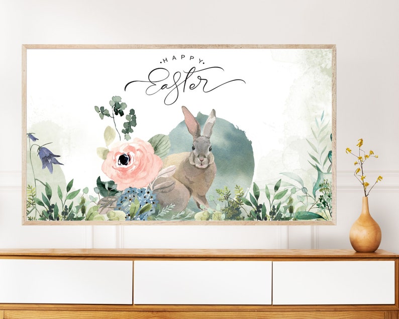 May include: A watercolor painting of two rabbits in a floral setting. The rabbits are brown and gray with long ears. The flowers are pink, blue, and green. The text "Happy Easter" is written in cursive at the top of the painting.