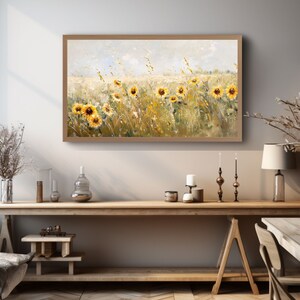 May include: A framed painting of a field of sunflowers in a rustic setting. The sunflowers are yellow with brown centers and are surrounded by green grass and brown stems. The background is a light blue sky with white clouds.