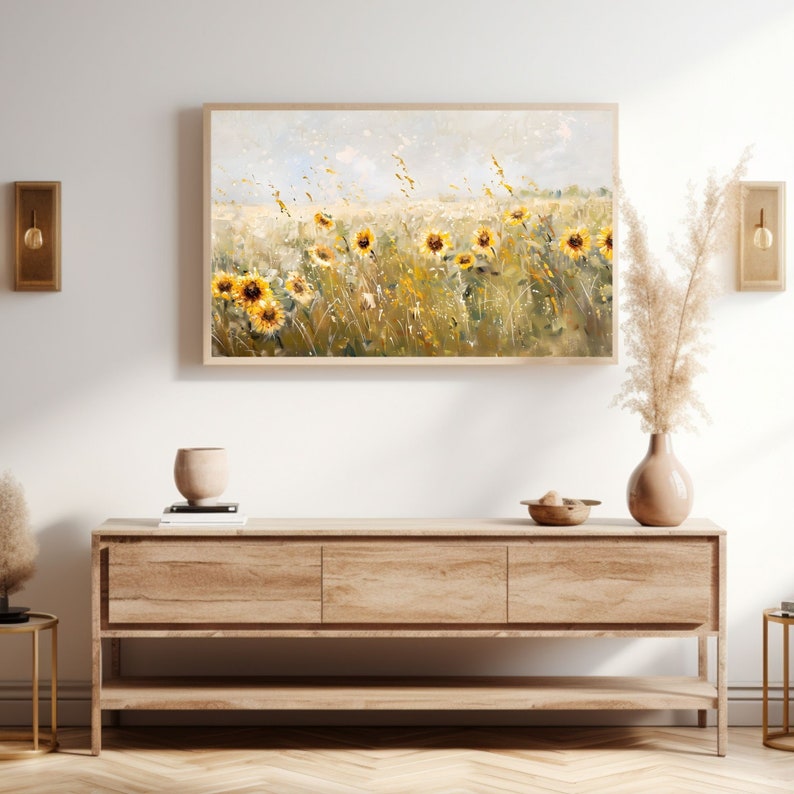 May include: A framed painting of a field of sunflowers in a light blue sky. The sunflowers are yellow with brown centers and the field is green with brown grass. The painting is in a light wood frame.