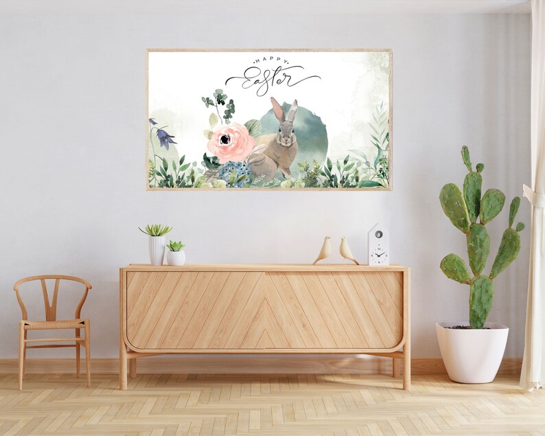 May include: A watercolor print featuring a rabbit with a pink flower and green foliage. The print has the text "Happy Easter" written in cursive.