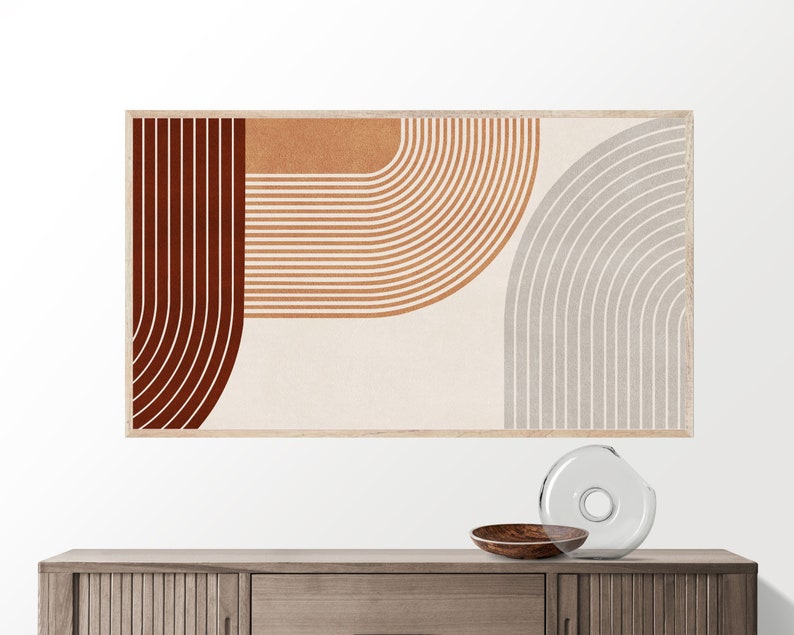 May include: Abstract art print with a geometric design featuring curved lines in shades of brown, orange, and gray. The print is framed in a light wood frame.