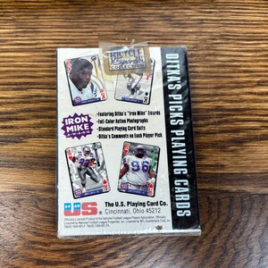 Pode incluir: Um baralho de cartas Bicycle Sports Collection com Ditka's Picks. A caixa inclui imagens de jogadores de futebol americano e o texto "Iron Mike A-W-A-R-D". O baralho &eacute; da The U.S. Playing Card Co., Cincinnati, Ohio.