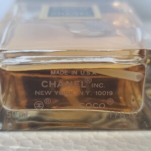K&ouml;nnte beinhalten: Ein klarer Glasparf&uuml;mflakon mit einer goldenen Fl&uuml;ssigkeit im Inneren. Auf der Unterseite der Flasche steht "MADE IN U.S.A.", "CHANEL INC.", "NEW YORK, N.Y. 10019" und "COCO". Die Flasche enth&auml;lt 50 ml / 1,7 fl oz.