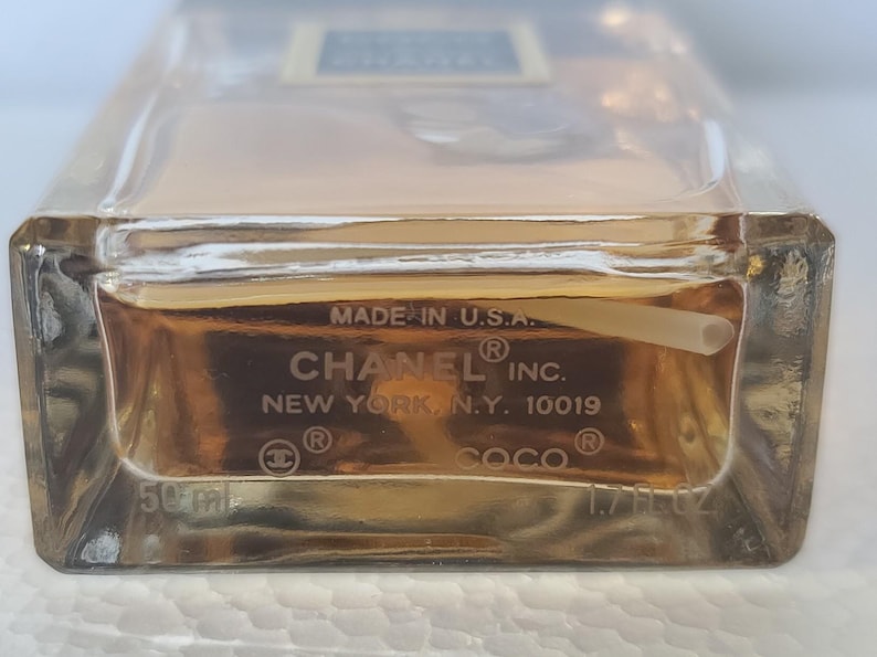 K&ouml;nnte beinhalten: Ein klarer Glasparf&uuml;mflakon mit einer goldenen Fl&uuml;ssigkeit im Inneren. Auf der Unterseite der Flasche steht "MADE IN U.S.A.", "CHANEL INC.", "NEW YORK, N.Y. 10019" und "COCO". Die Flasche enth&auml;lt 50 ml / 1,7 fl oz.