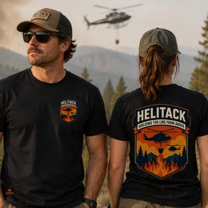 May include: A black t-shirt featuring a graphic of helicopters over a forest fire with the text HELITACK HOLDING THE LINE FROM ABOVE. The design appears on the left chest and as a larger print on the back, depicting orange flames and trees.