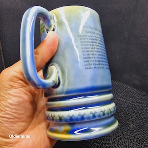 May include: A blue and white ceramic mug with a handle. The mug has a Celtic design and a quote about the Giant's Causeway in Northern Ireland. The quote reads: "Legend has it that this Causeway was built by Giants. This Causeway was built by Giants. It is also said that a giant gave at the end of man by throwing a stone at an enemy in a fight. The area for the stone dropped in the sea and drifted filled with water. Near in Ulster."