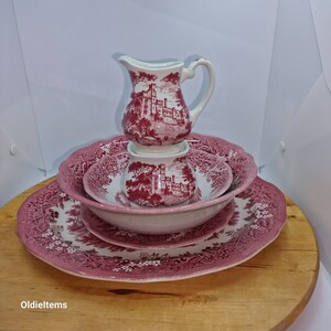 Puede incluir: Un juego de platos de porcelana rosa y blanca con un patrón floral. El juego incluye una jarra de crema, un azucarero, un tazón pequeño y una fuente grande.