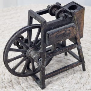 以下が含まれることがあります： 暗い茶色の金属製の、荷車の車輪の形をしたヴィンテージスタイルの鉛筆削り。 鉛筆削りは、片側に大きな車輪、反対側に長方形のハウジングを備えています。 「EAGLE」の文字が見えます。 コレクションアイテムです。