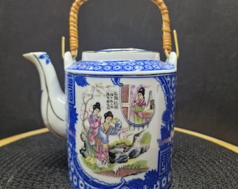 May include: A vintage porcelain teapot with a woven handle. The teapot features a blue and white floral design with illustrations of figures in traditional clothing. The spout and lid are white with blue accents.
