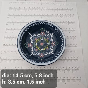 K&ouml;nnte beinhalten: Eine kleine, blaue Keramikschale mit wei&szlig;em Rand und einem floralen Design in Rosa, Gelb und Wei&szlig;. Die Schale misst 14,5 cm im Durchmesser und 3,5 cm in der H&ouml;he.