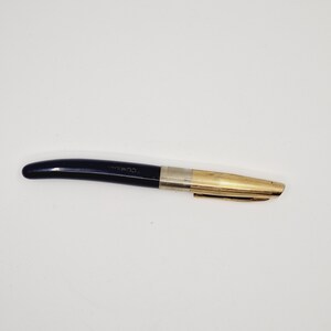 Peut inclure: Un stylo plume noir et or avec le mot "Commodore" gravé sur le corps noir.