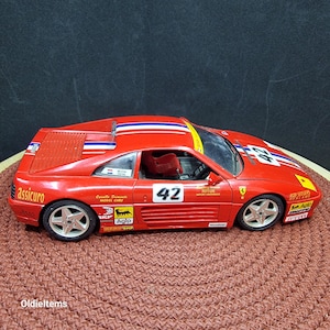 Burago-modelauto Ferrari 348 TB (1989) in rode kleur, een gegoten schaalmodel van 1/18, gebruikt, de lampen zijn geverfd. Er zitten veel stickers op.