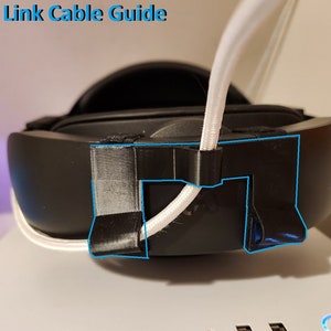May include: Black VR headset with a white cable held by a black 3D-printed cable guide. The text "Rear Link Cable Guide" is at the top. The headset is on a white surface.