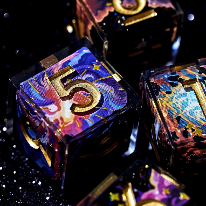 May include: Close-up of several dice with a celestial theme. The dice are clear with colorful, swirling designs in shades of blue, purple, and gold. Each die has a large, gold number on its face, with a glittery black background.