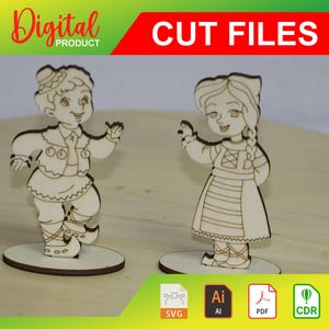 Könnte beinhalten: Zwei ausgeschnittene Holzfiguren eines Jungen und eines Mädchens in traditionellen Trachten. Die Figuren stehen auf separaten Sockeln und sind zum Ausschneiden bereit. Das Bild enthält den Text "CUT FILES" und "SVG, AI, PDF, CDR".