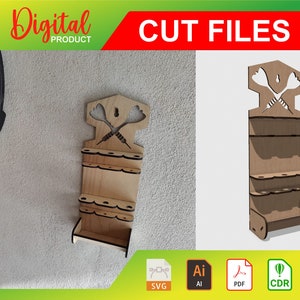 Może przedstawiać: Cyfrowe pliki do cięcia do pobrania dla drewnianego stojaka na lotki. Stojak ma półkę na lotki i ozdobny górny element z krzyżującymi się lotkami. Pliki są dostępne w formatach SVG, AI, PDF i CDR.