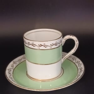 May include: A green and white porcelain teacup and saucer set with gold trim and a delicate floral design.