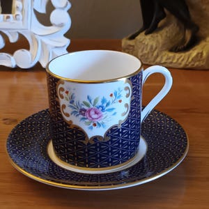 May include: A blue and gold teacup and saucer set with a floral design. The cup has a gold rim and a white interior. The saucer has a matching design.