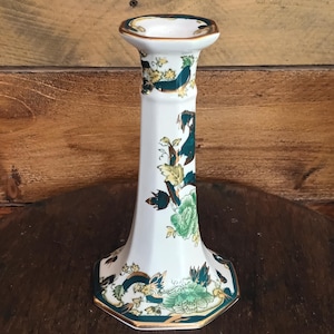 Puede incluir: Candelabro de cerámica blanca con base acampanada y cuerpo largo y delgado. El candelabro está decorado con motivos florales verdes y dorados. El borde y la base están adornados con oro. Diseñado para una sola vela.