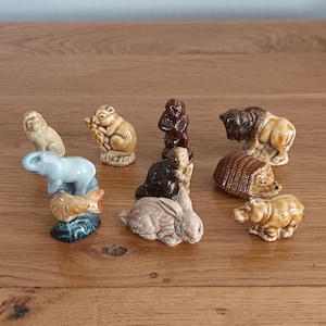 Puede incluir: Colección de pequeñas figuras de animales de cerámica, que incluyen un león, un mono, un elefante, un pez, un oso, un conejo, un castor, un bisonte, un erizo y un pequeño oso. Las figuras son de color marrón, beige y gris.