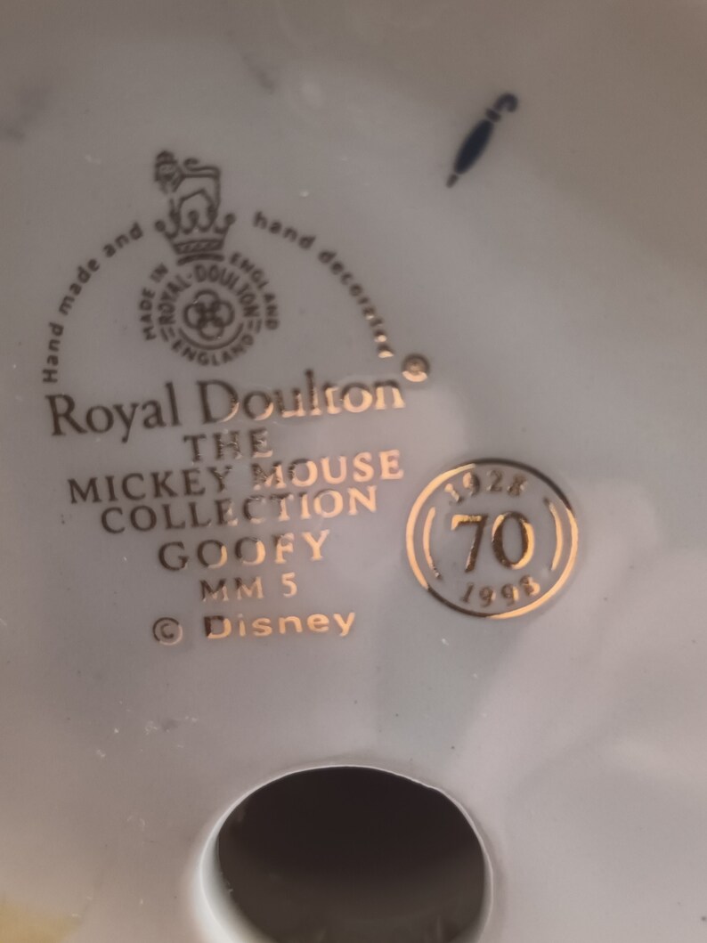 May include: A gold Royal Doulton figurine of Goofy from the Mickey Mouse Collection. The figurine is marked with the year 1996 and the number 70. The text "Hand made and hand decorated" is visible on the base.
