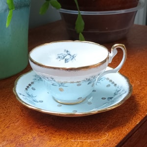 May include: A blue and white teacup and saucer with a gold trim and floral design. The saucer has a scalloped edge.