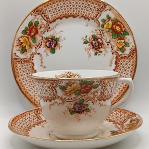 May include: A vintage teacup and saucer set with a brown and white floral pattern. The set features a delicate floral design with gold accents.