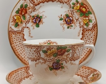 May include: A vintage teacup and saucer set with a brown and white floral pattern. The set features a delicate floral design with gold accents.