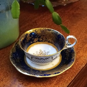 May include: A blue and gold teacup and saucer set with intricate floral and geometric patterns. The cup has a white interior and a gold rim.