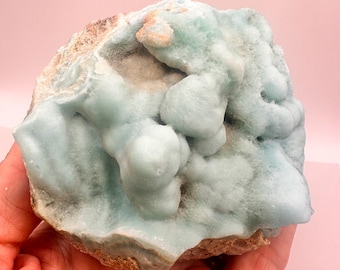 Op de afbeelding: Een grote, lichtblauwe, groene en witte celestietkristalcluster met een ruw, getextureerd oppervlak.