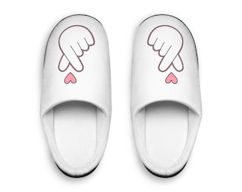 May include: A pair of white slippers with a pink heart and a hand gesture on each slipper.