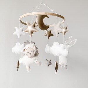 May include: A white and gold baby mobile with a lamb, a bunny, clouds, and stars hanging from a wooden ring.