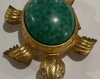 Porta perfume compacto vacío con diseño de tortuga marina en tono dorado y dorso verde moteado de Avon