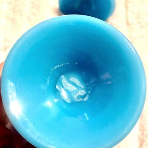 May include: A close-up of the inside of a turquoise blue glass bowl. The bowl is smooth and shiny, with a slight iridescent sheen.