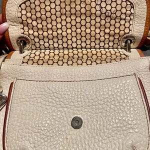 Peut inclure: Sac &agrave; main en cuir blanc avec une doublure &agrave; pois marrons. Le sac a une fermeture &agrave; rabat et une petite poche sur le devant.