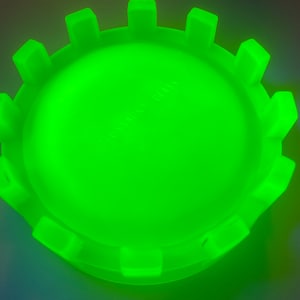May include: A bright green glass ashtray with a scalloped edge. The ashtray has the words "Fusion Glass" embossed on the bottom.